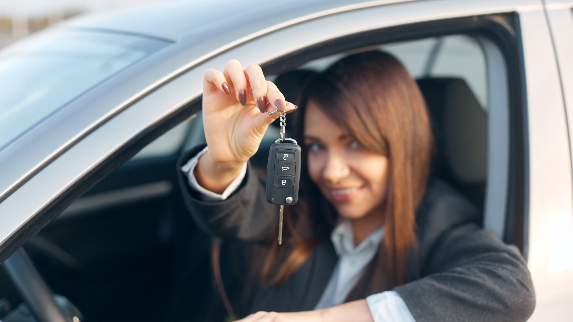 Business professional holding car keys inside a vehicle, representing monthly car rental in San Francisco