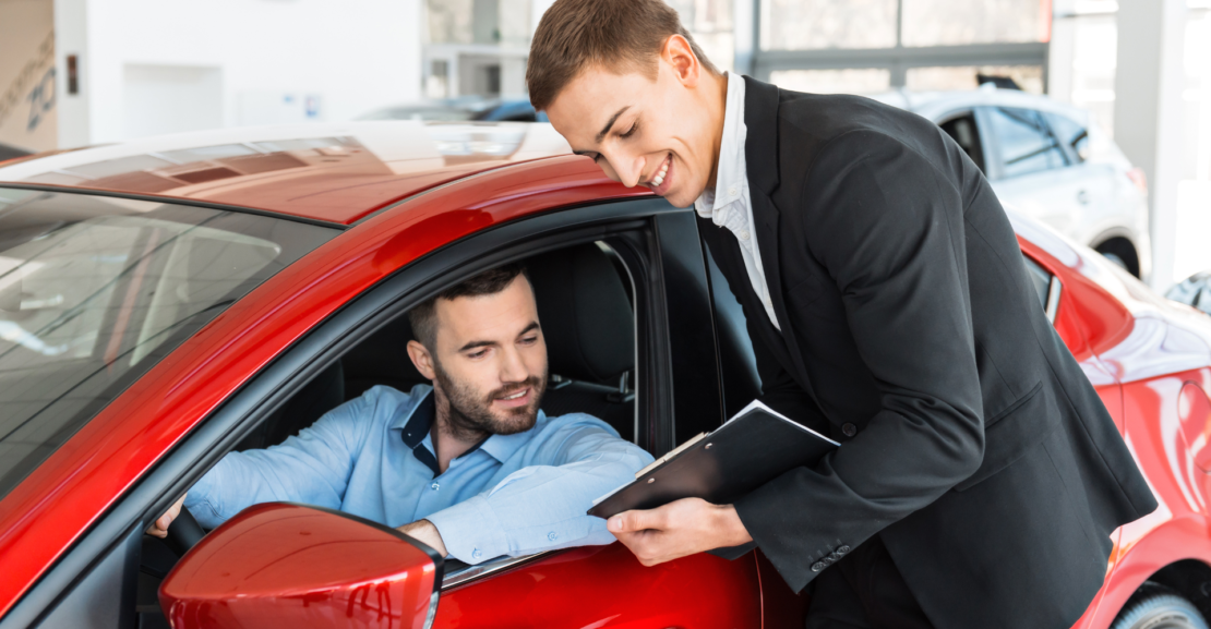 Customer reviewing car rental details with agent at dealership, representing long-term car rental service